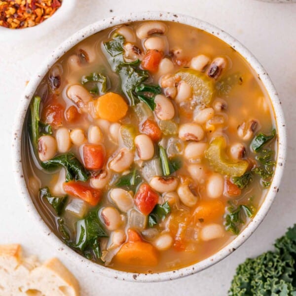 A bowl of vegetable and black-eyed pea soup with black-eyed peas, kale, carrots, celery, and diced tomatoes.