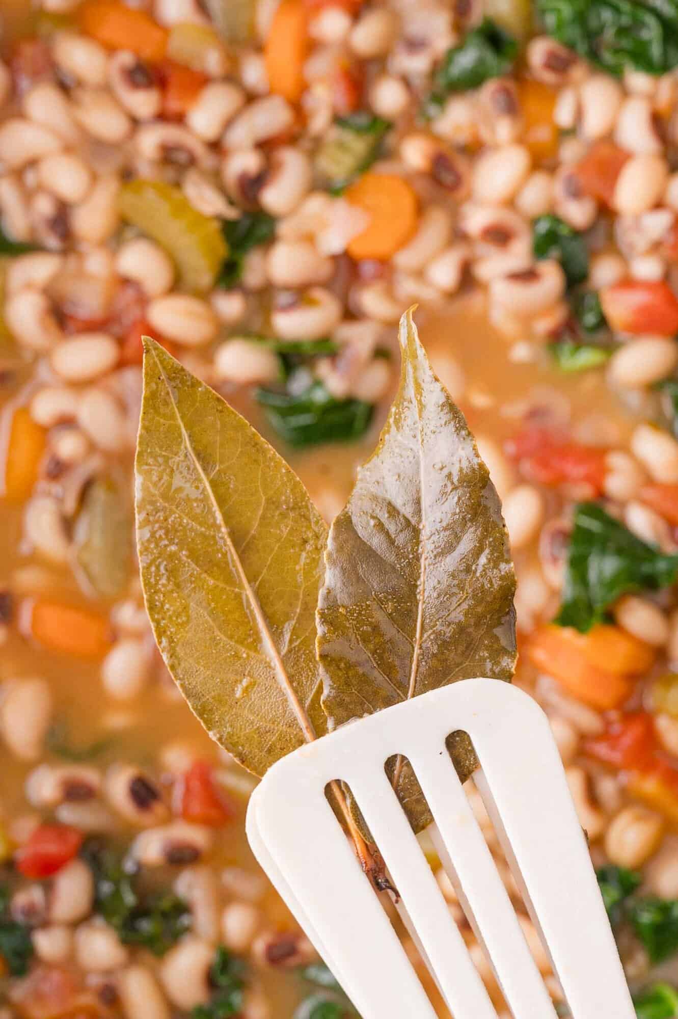 Black-Eyed Pea Soup 16 Two bay leaves held on a slotted spatula above a pot of vegetable and black-eyed pea soup.