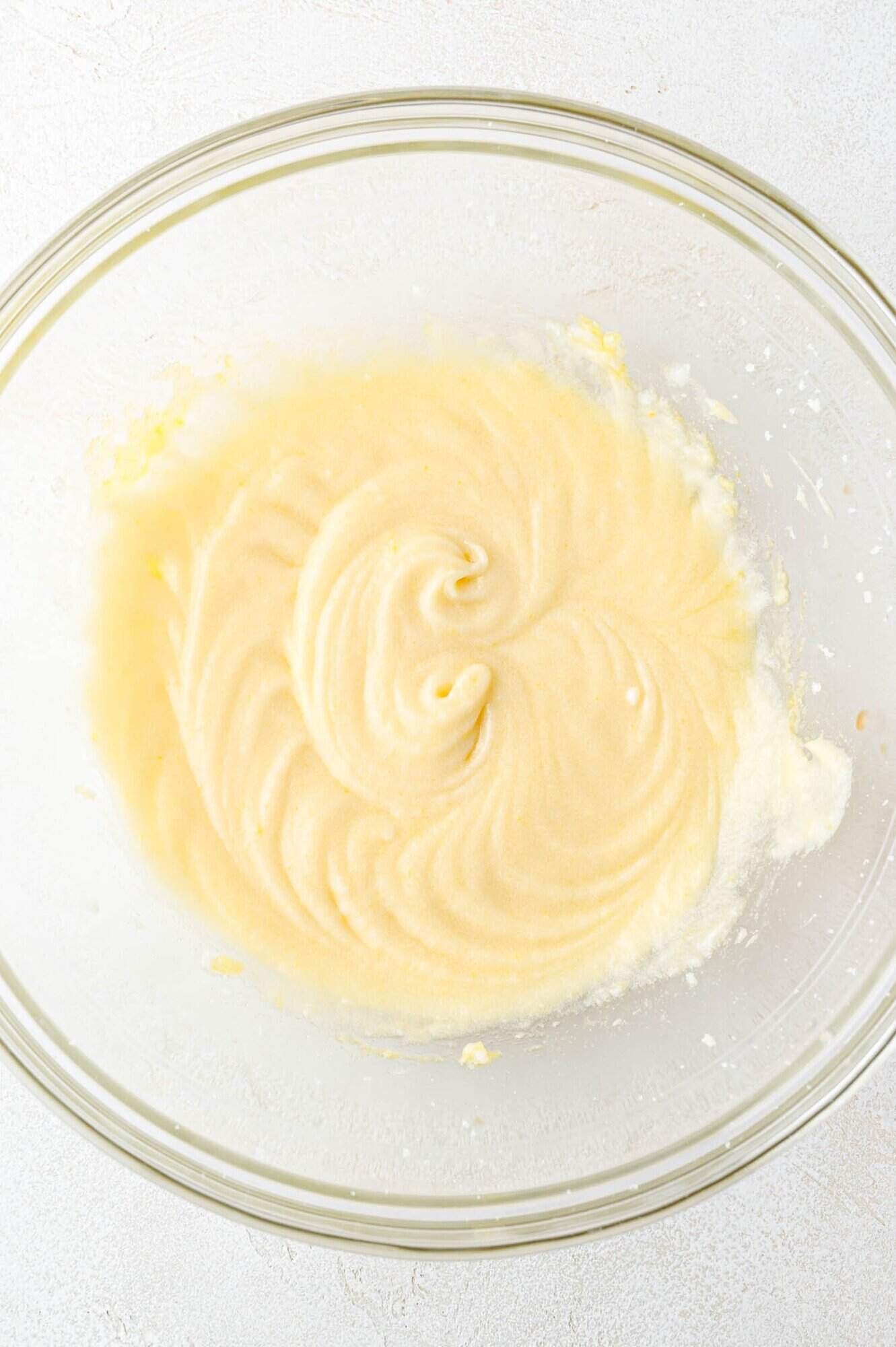 A clear glass bowl containing a smooth, creamy batter mixture with visible swirls on the surface.