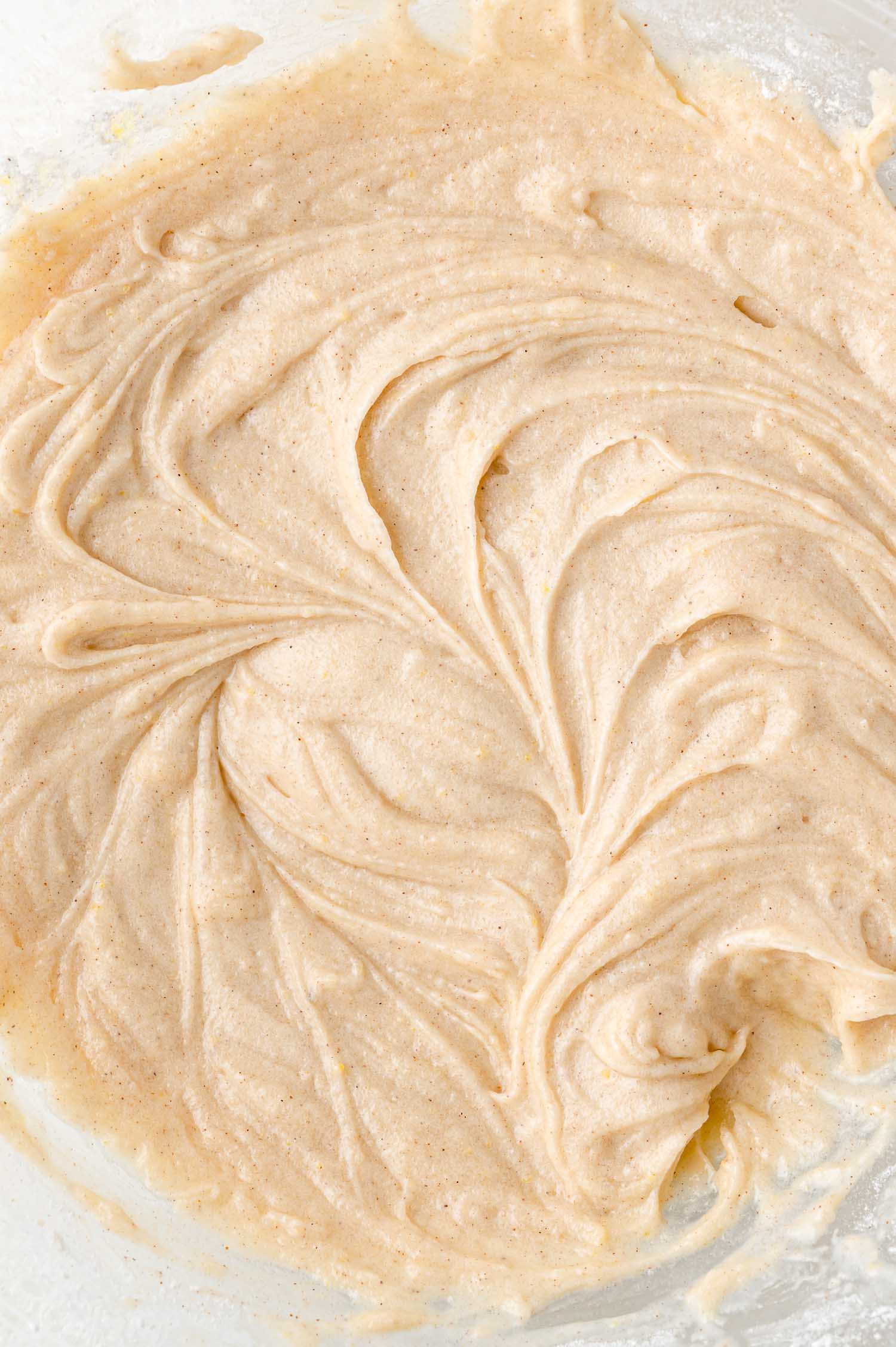 Close-up of a bowl filled with smooth, light brown cake batter, swirled with visible streaks and a slightly creamy texture.
