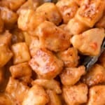 Close-up of bite-sized chicken pieces coated in a creamy orange bang bang sauce.