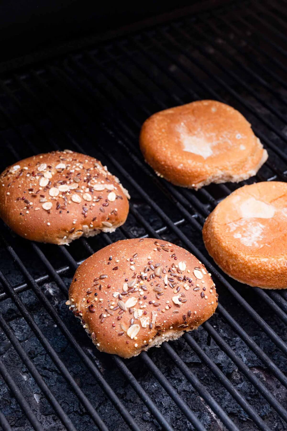 Two hamburger buns are toasting on a grill.