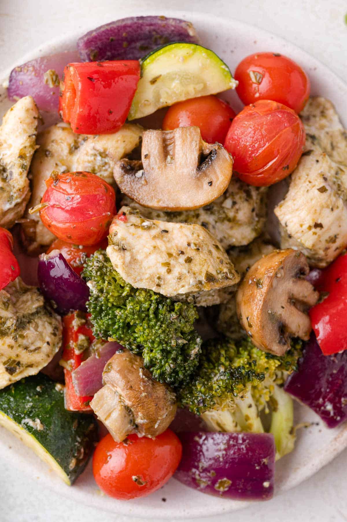 A plate of cooked sheet pan pesto chicken and vegetables.