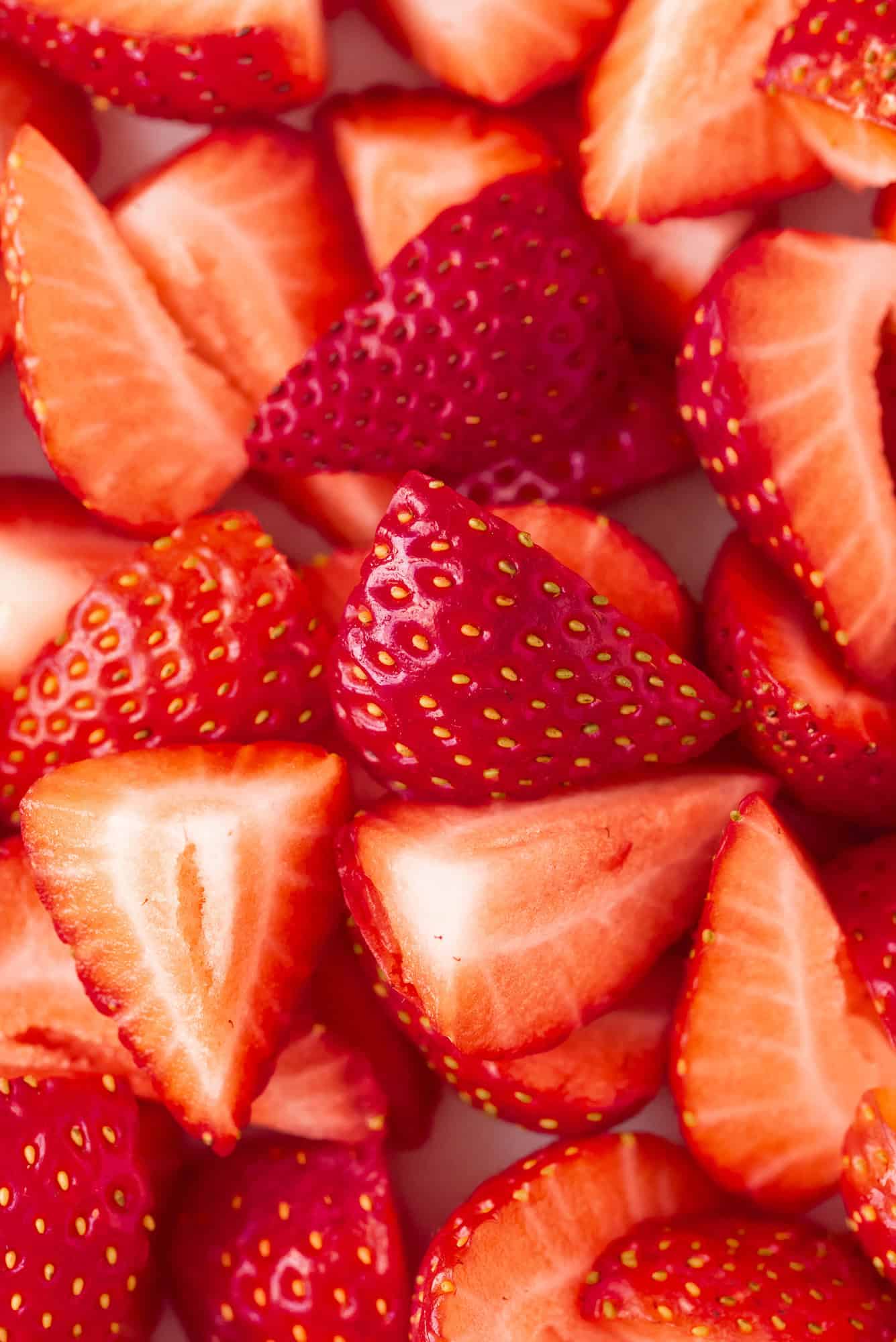 Close-up of fresh strawberries sliced in half, showing their red flesh and seeds.