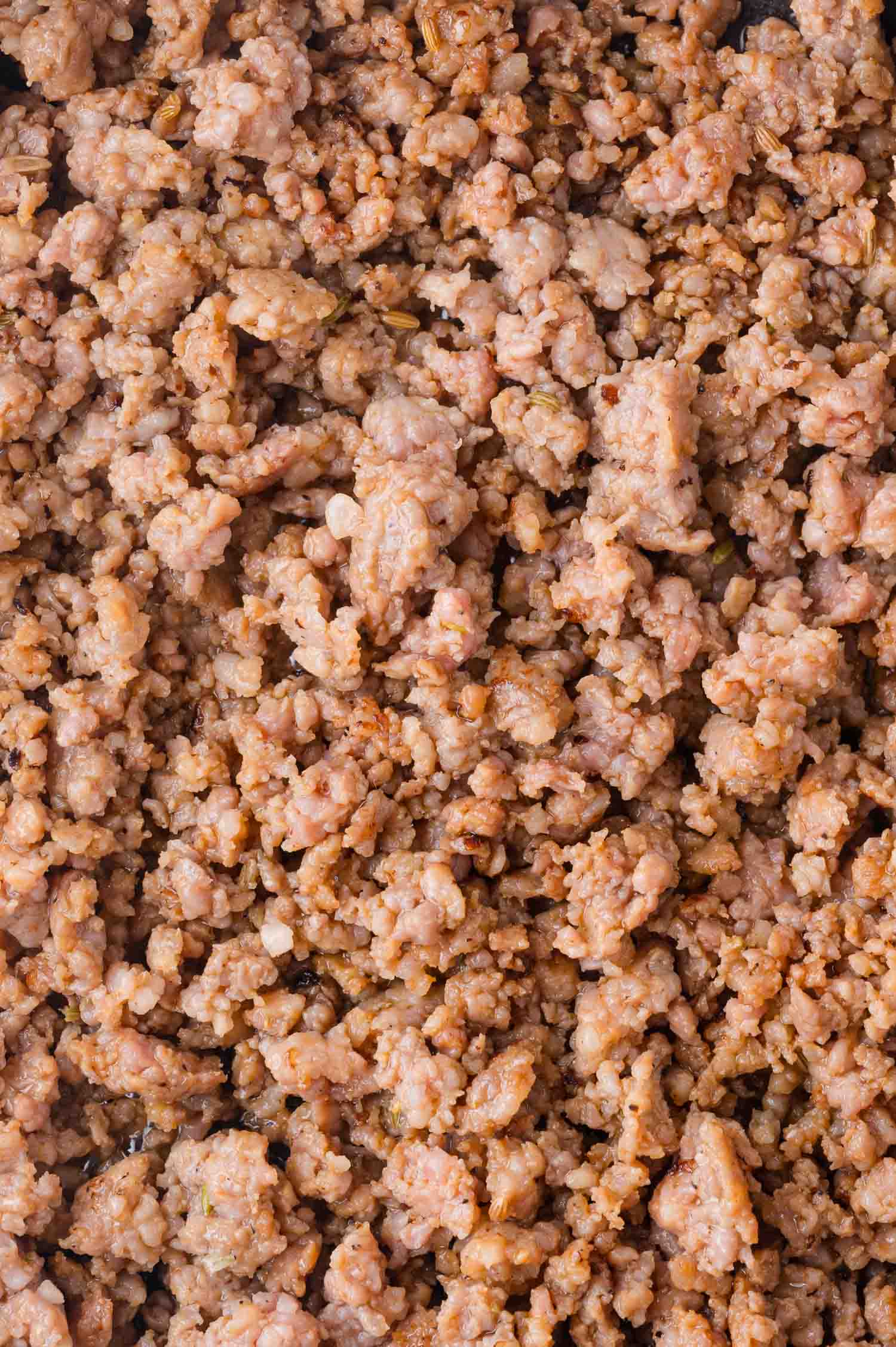 Cooked ground sauce crumbles, light brown in color, spread out in an even layer.