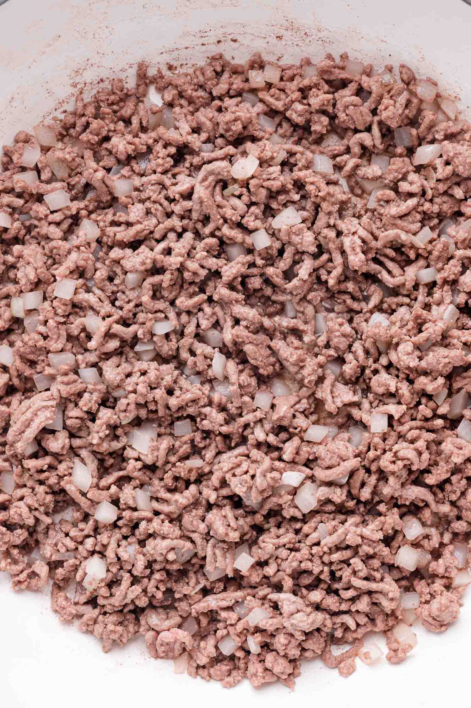 Ground beef and chopped onions cooking together in a pan.