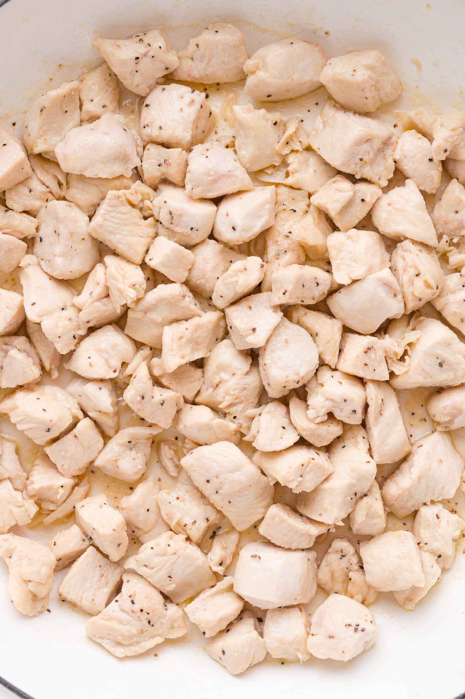 Cooked, diced chicken breast pieces seasoned with salt and black pepper, shown in a close-up top-down view.