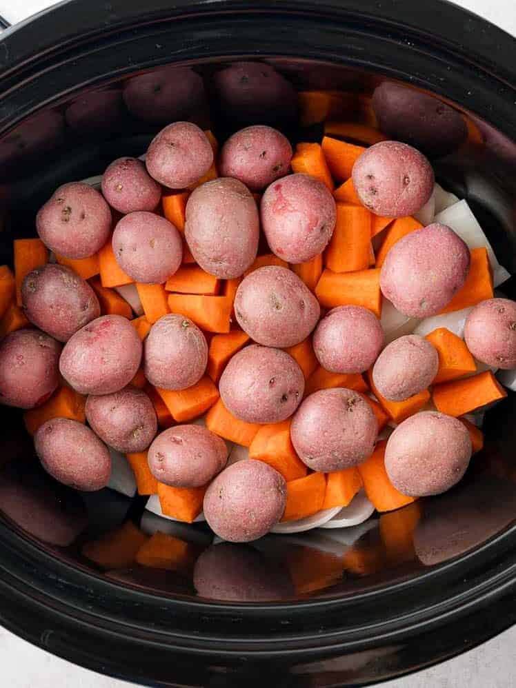 Uncooked potatoes and carrots in slow cooker.