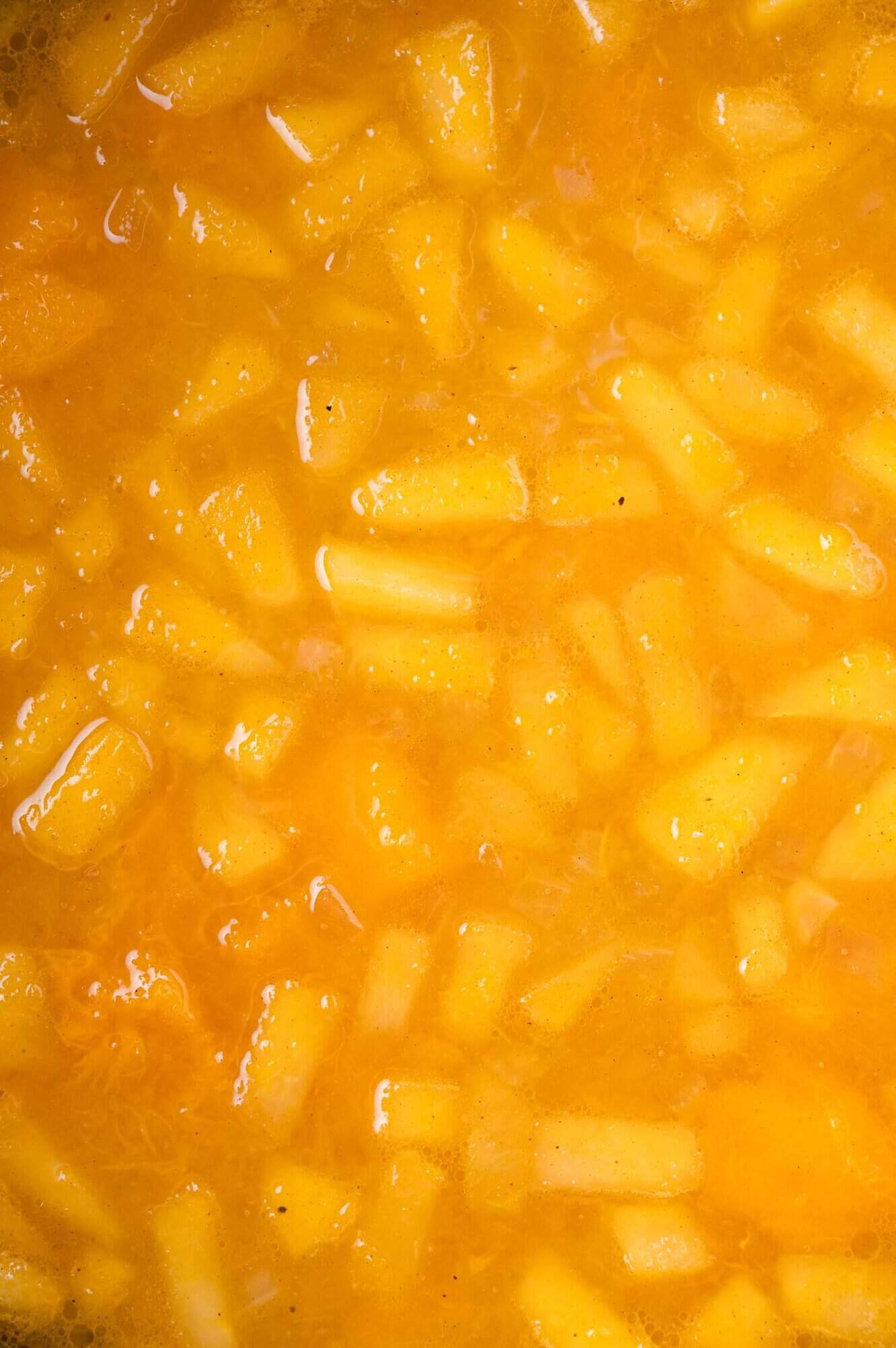 Close-up of cooked chopped apples floating in a squash soup, not yet pureed.