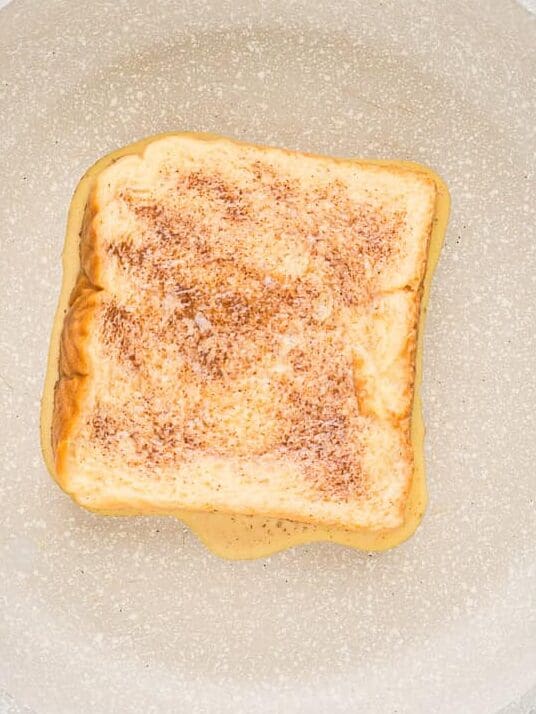 French toast, partially cooked, in a frying pan.