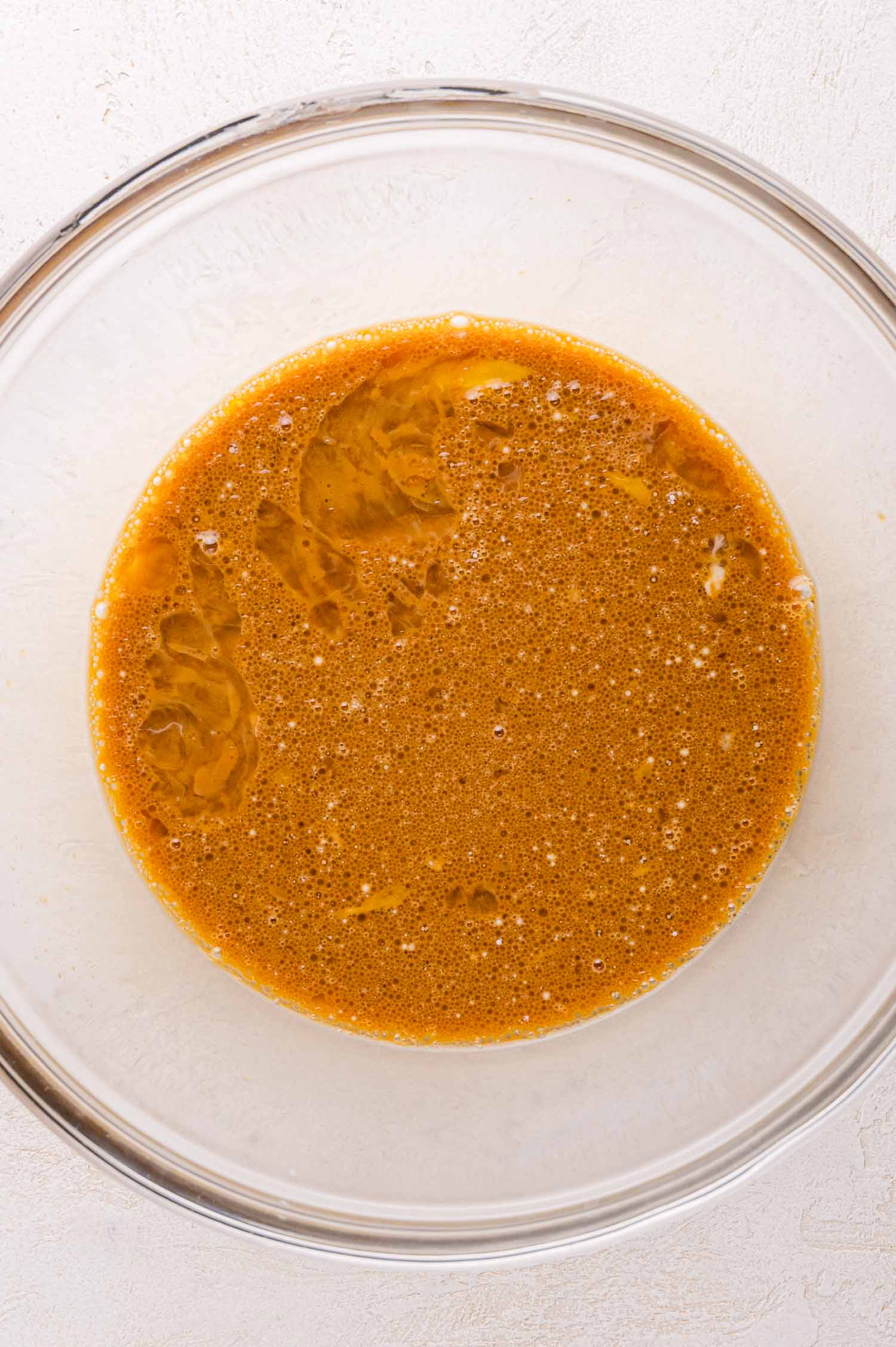 A glass bowl with the wet ingredients for the pancakes.