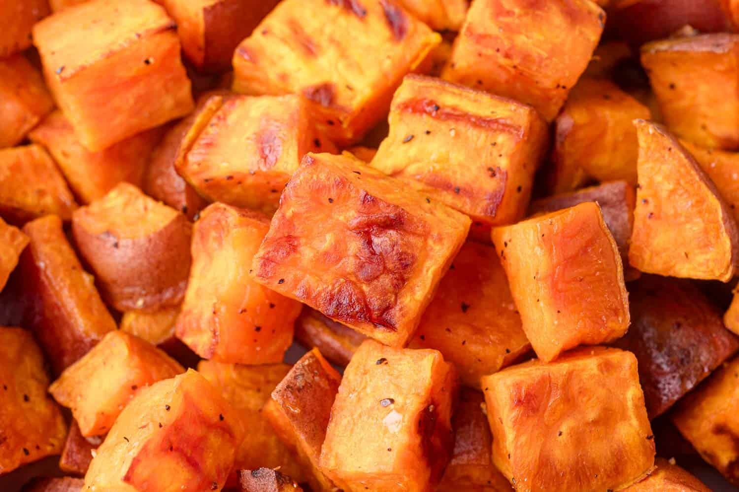 Close-up of roasted sweet potato cubes with a golden brown exterior, lightly seasoned and arranged in a pile.
