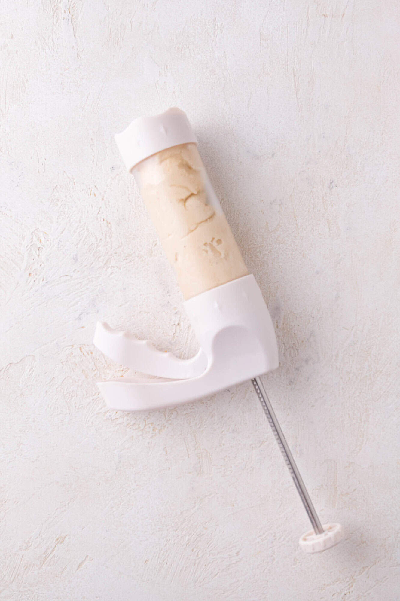 A cookie press full of cookie dough, on a white surface.