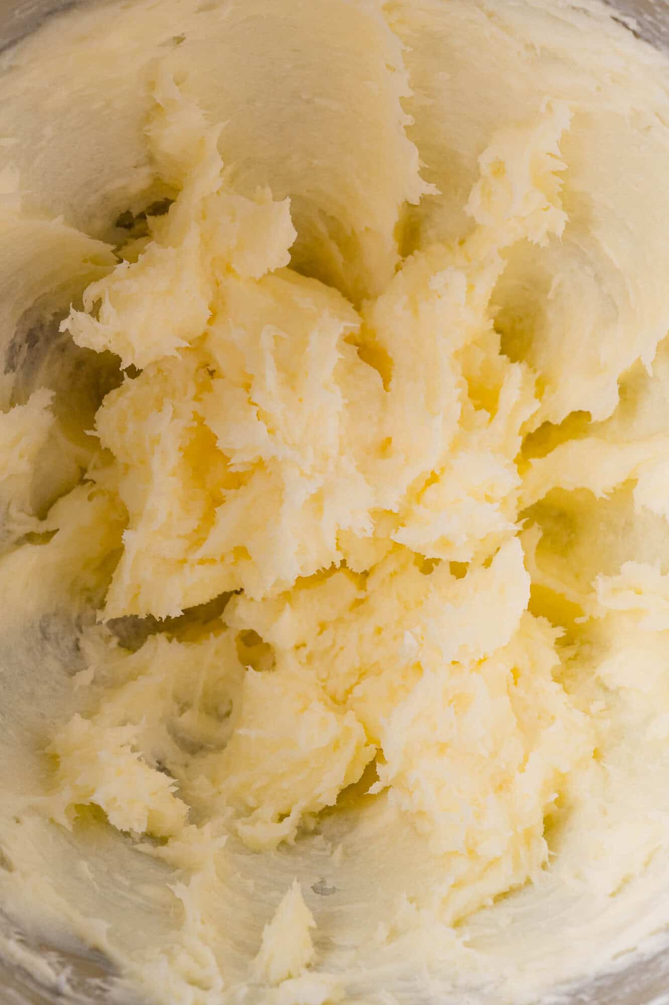 Soft, pale yellow butter and sugar mixture whipped together in a mixing bowl, showing a creamy, fluffy texture.
