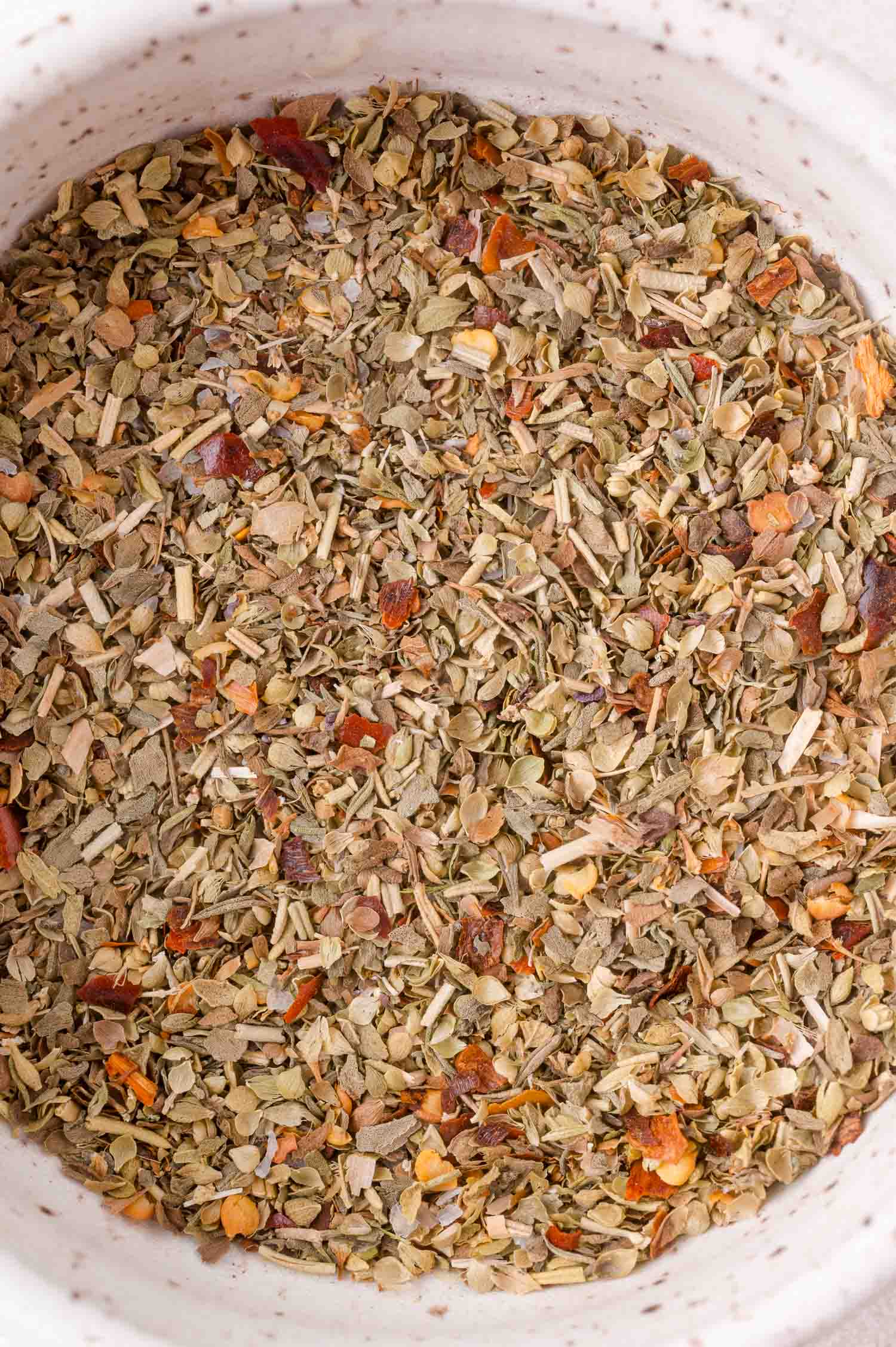 Close-up view of a bowl filled with a mixed dried herb seasoning blend.