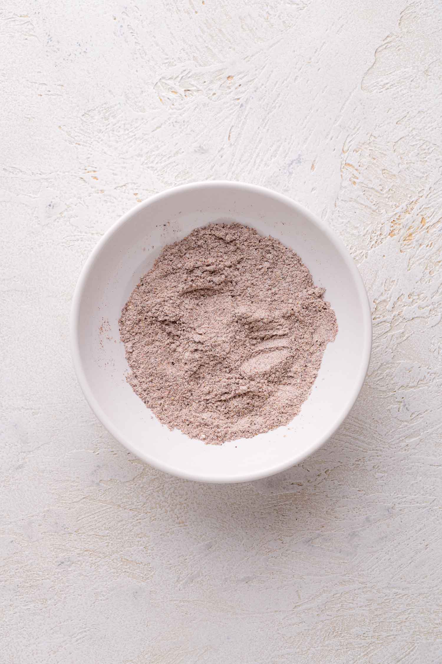 A white bowl containing a mound of flour and spices.