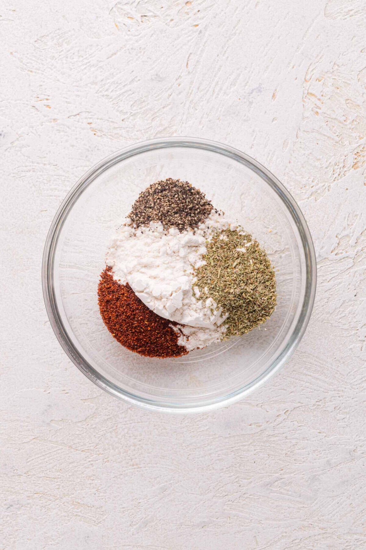 A bowl of spices in a white surface.