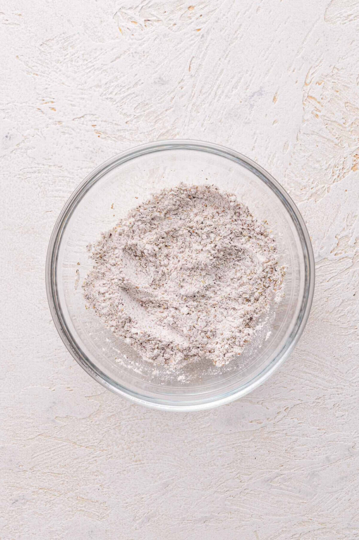 A glass bowl filled with a mixture of flour and spices.