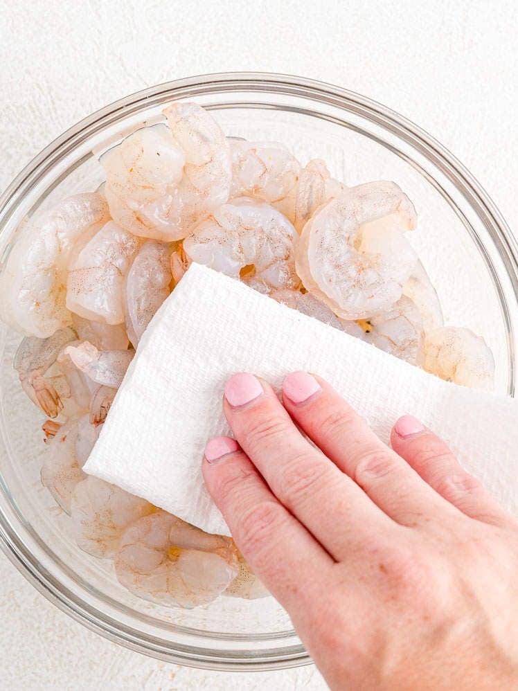 Thawed shrimp being patted dry.