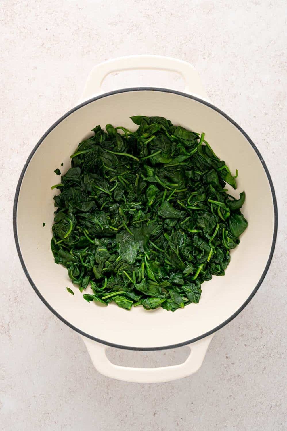 Wilted spinach leaves in a large white pot.