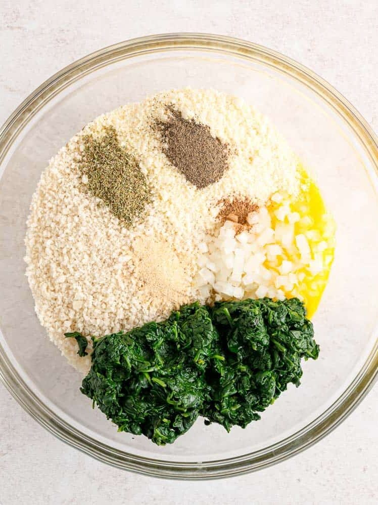 Spinach ball ingredients combined in a glass bowl.
