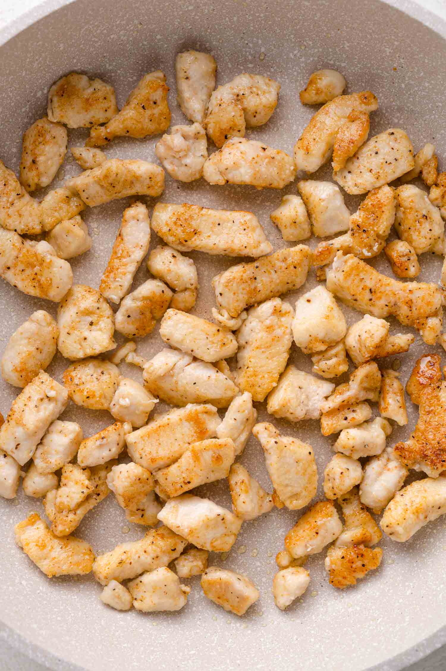 Cooked, seasoned chicken pieces in a frying pan.