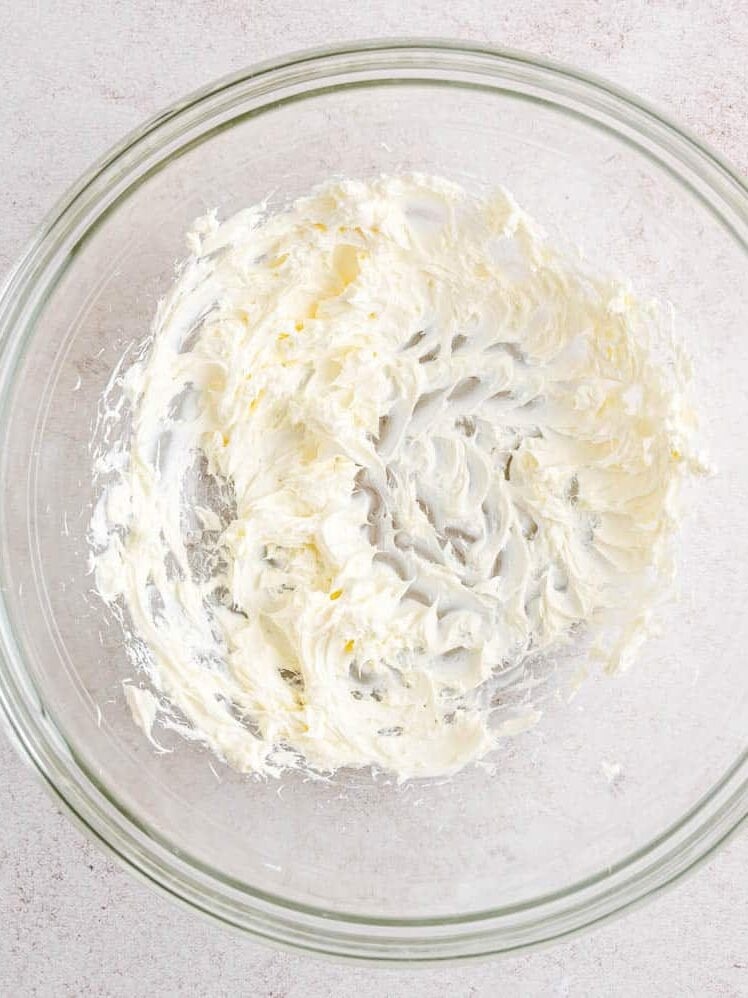 Beaten cream cheese in a glass mixing bowl.