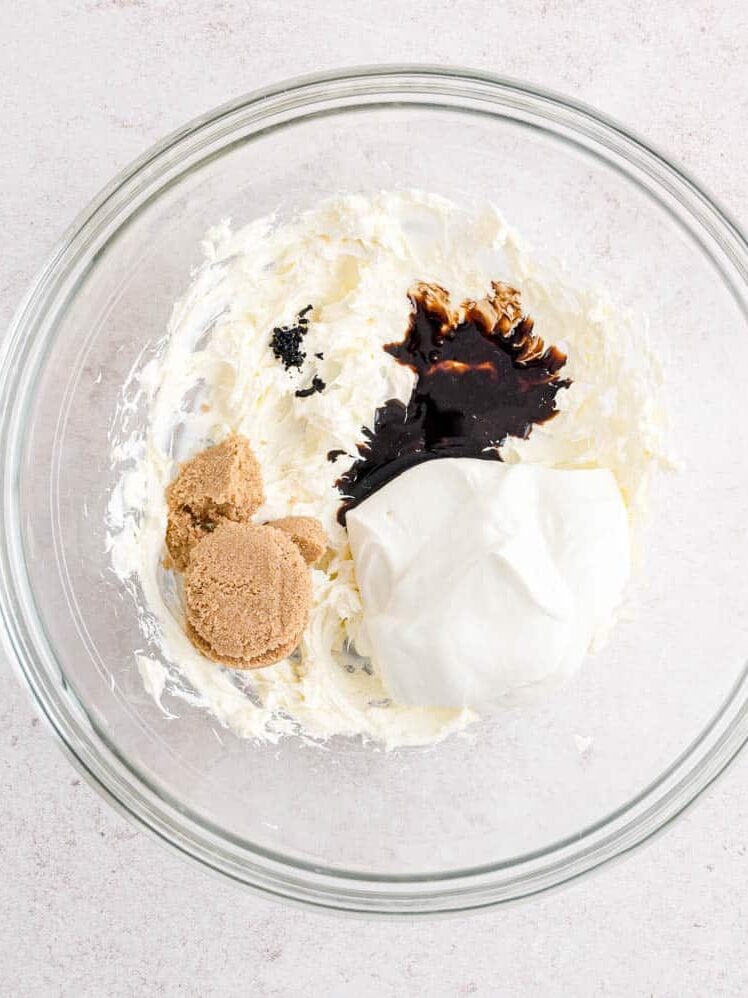 Ingredients for cream cheese fruit dip added to a mixing bowl with beaten cream cheese.
