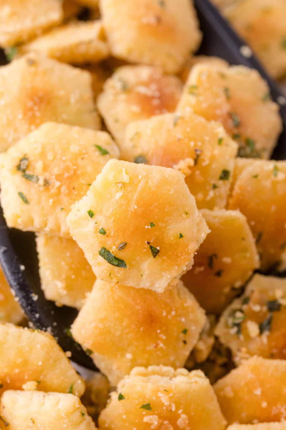 Hexagonal crackers coated with herbs and seasoning, shown in a close-up view.