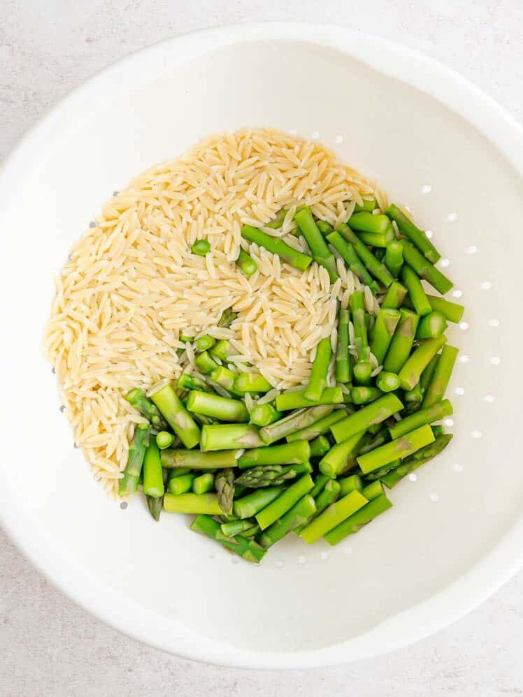Orzo and asparagus in colander.