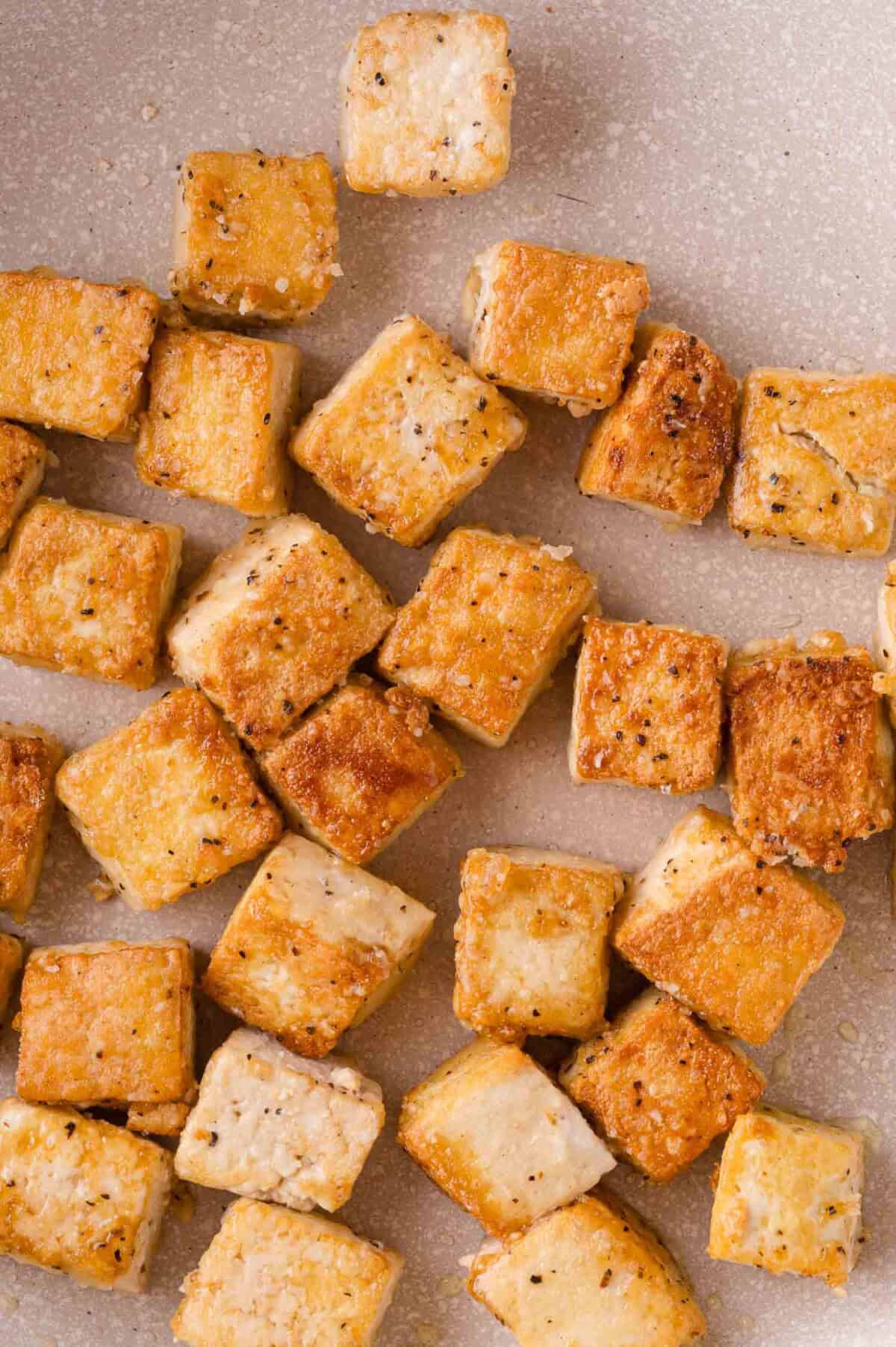 Golden brown cubes of seasoned and pan-fried tofu arranged in a pan.
