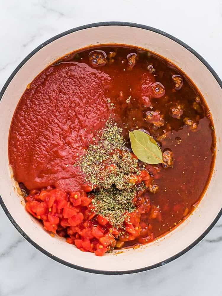 Tomatoes, bay leaf, and herbs added.