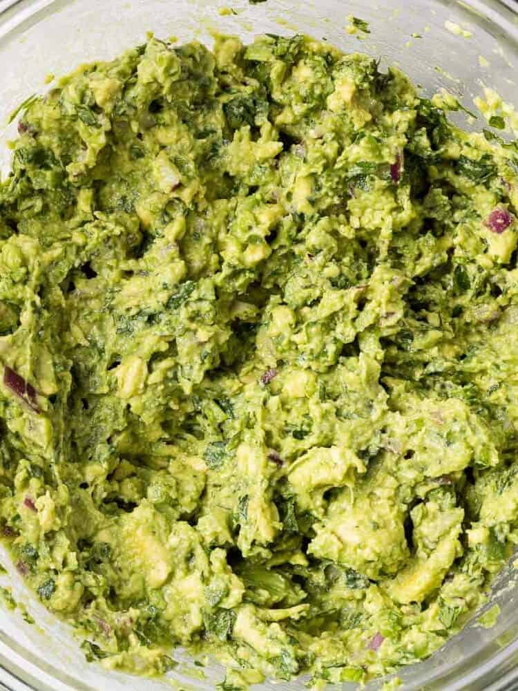 Guacamole in a clear glass mixing bowl.