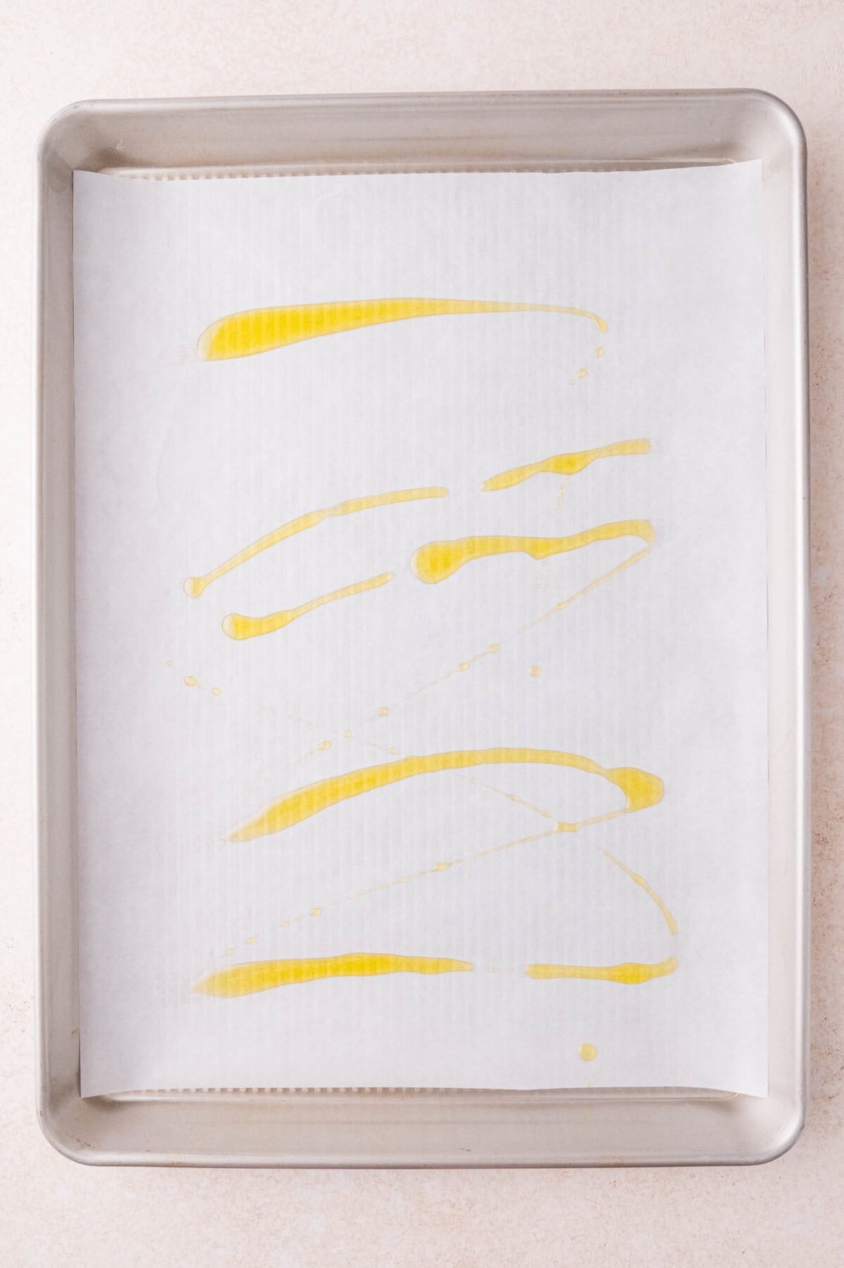 A baking sheet lined with parchment paper is drizzled with olive oil.