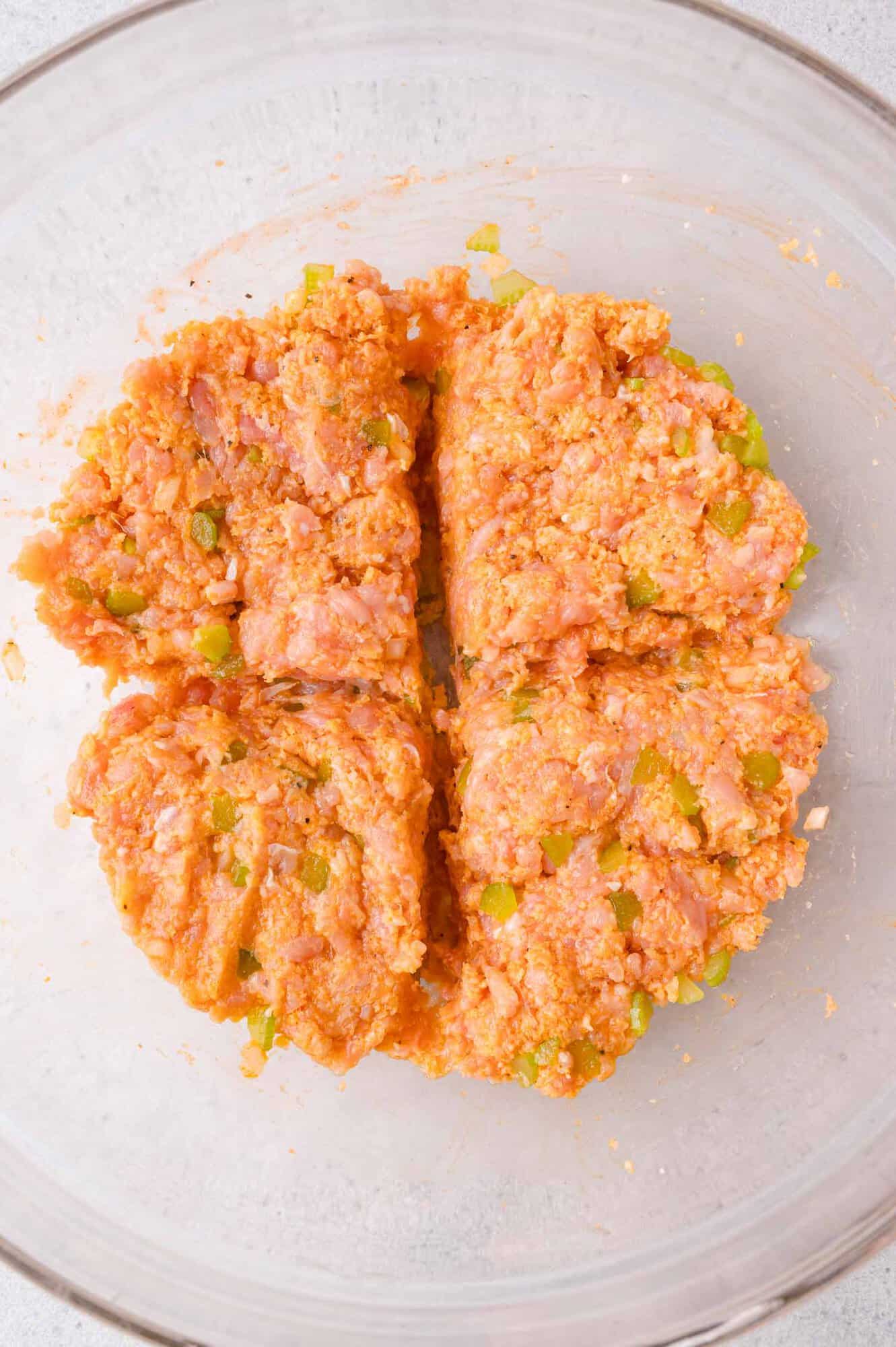 Ground chicken mixture with celery in a glass bowl, divided into four equal sections.