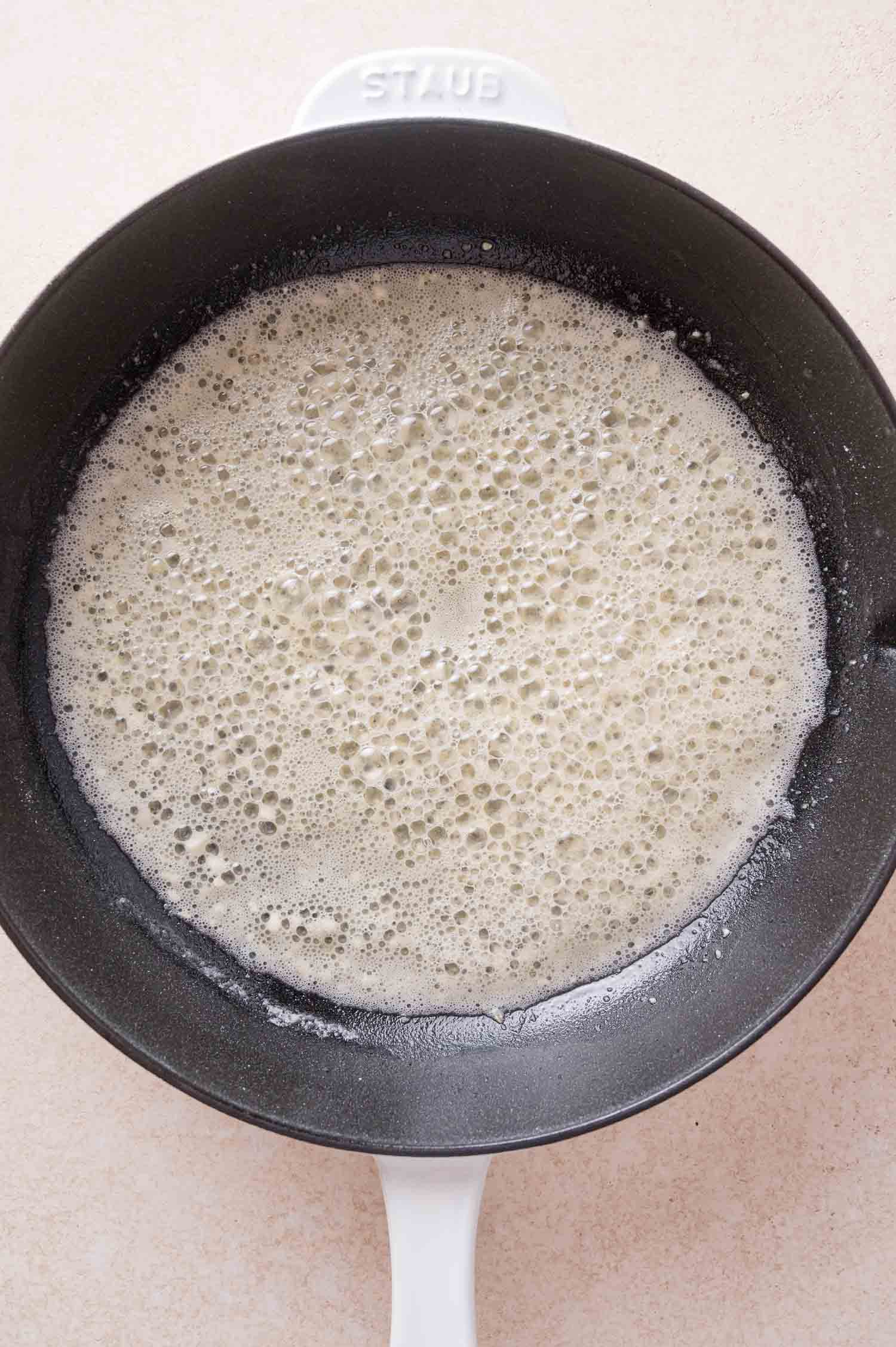 Butter foaming in a black Staub skillet.