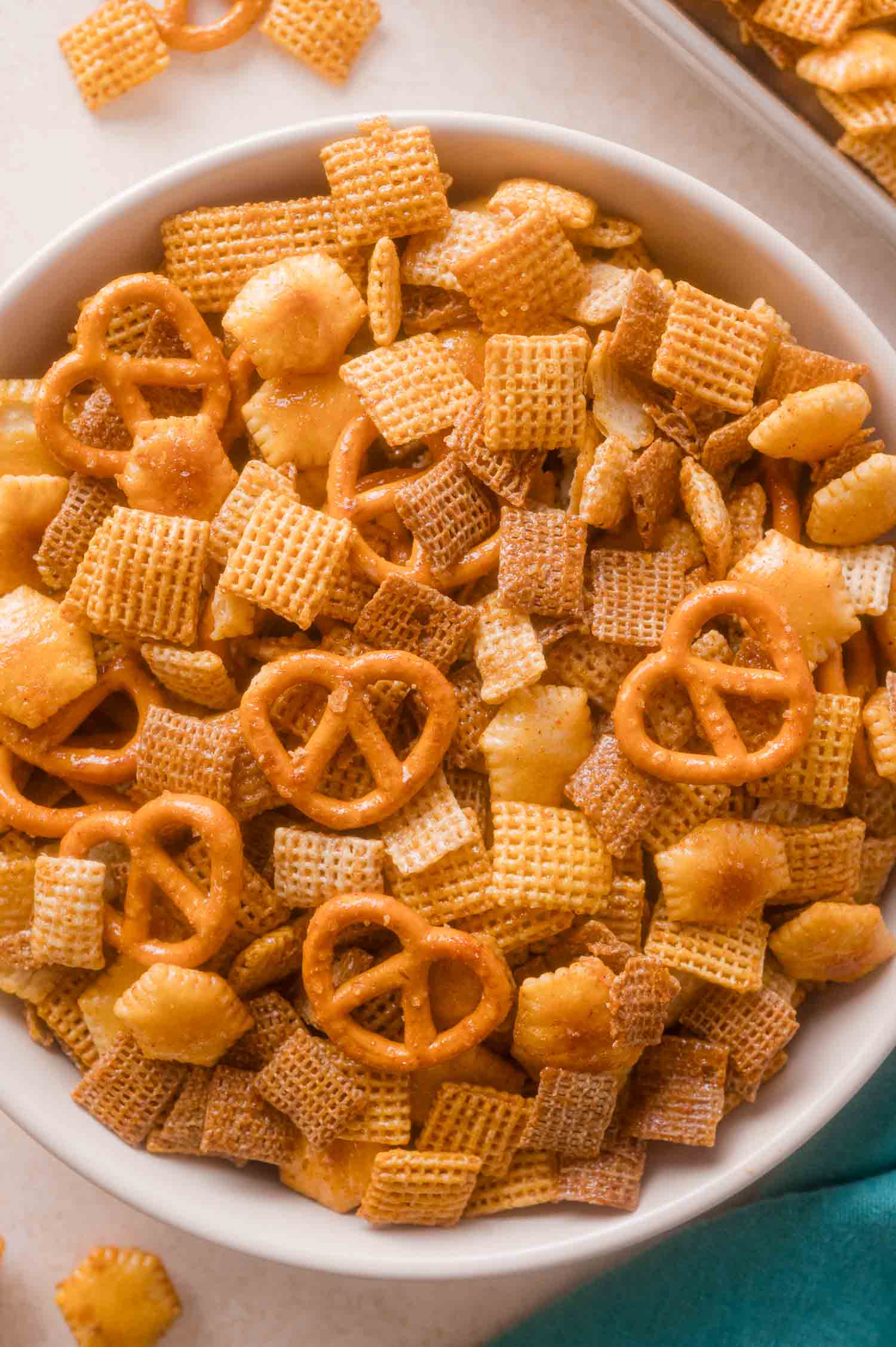 A bowl of seasoned hot honey Chex party mix containing cereal squares, pretzels, and crackers.